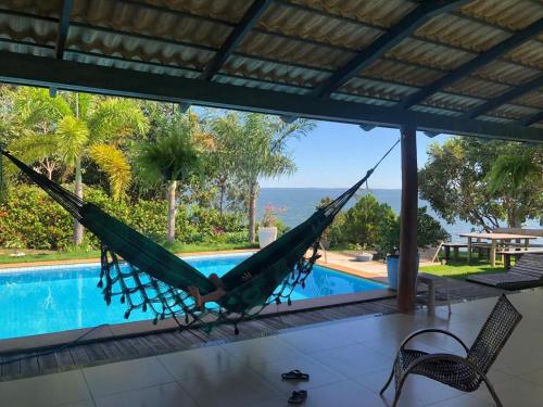 eine Hängematte in einem Zimmer mit Blick auf einen Pool in der Unterkunft Chácara Por do Sol Beira Lago in Palmas