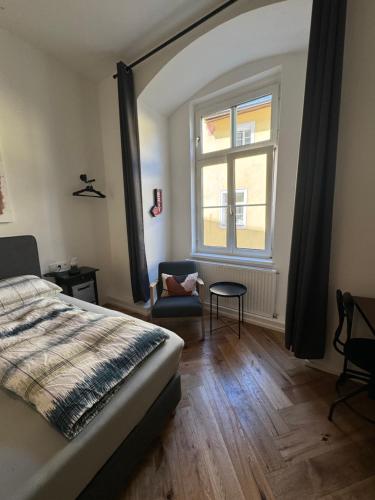 a bedroom with a bed and a chair and a window at Industrial Apartment Schlossberg in Linz