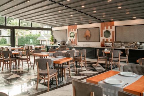 uma sala de jantar com mesas, cadeiras e janelas em Alfa Suites & SPA em Sapanca