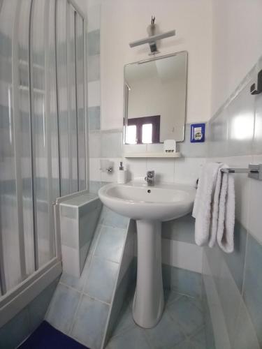 a white bathroom with a sink and a mirror at A casa SCALILLA in Palermo