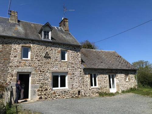 une personne debout à l'entrée d'une maison en pierre dans l'établissement Charmante maison normande à Brainville à 10mn de la mer, à Brainville
