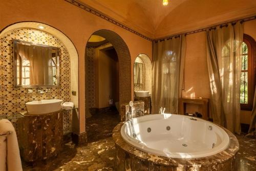 a large bathroom with a large tub and a large mirror at Palais FARAH in Marrakesh