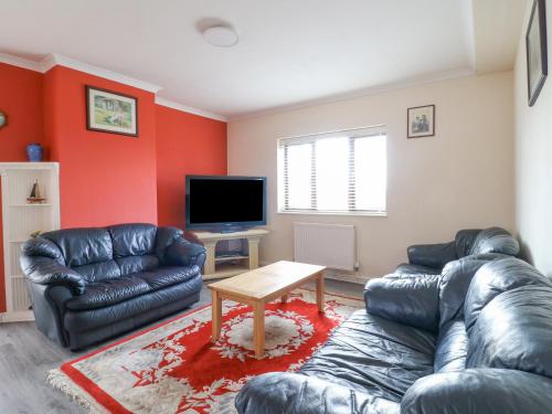 a living room with a leather couch and a table at Stensonhill Lodge in Derby