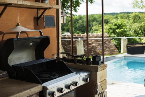 a kitchen with a stove and a swimming pool at Le Domaine des Carriers in Chevroches