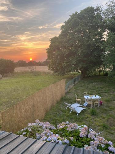 - une table et des chaises dans un champ au coucher du soleil dans l'établissement Charmante maison normande à Brainville à 10mn de la mer, à Brainville