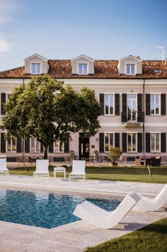 a large building with a swimming pool and white chairs at Villa Adelaide Relais & Wine in Calamandrana