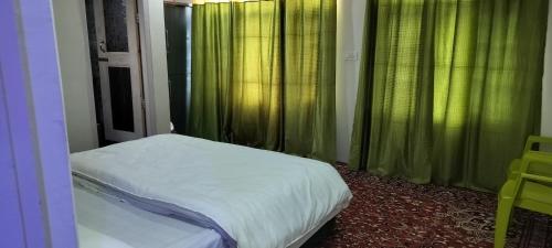 a bedroom with a bed and green curtains and a window at Elizabeth paying guest house Tangmarg gulmarg in Gulmarg