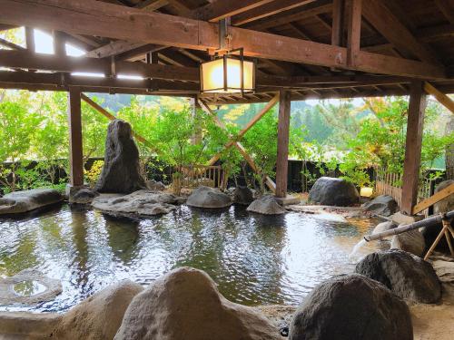 a pond in a building with rocks and a light at Kurasako Onsen Sakura in Minamioguni