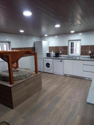 a large kitchen with white cabinets and a wooden floor at Casa do Moinho in Resende