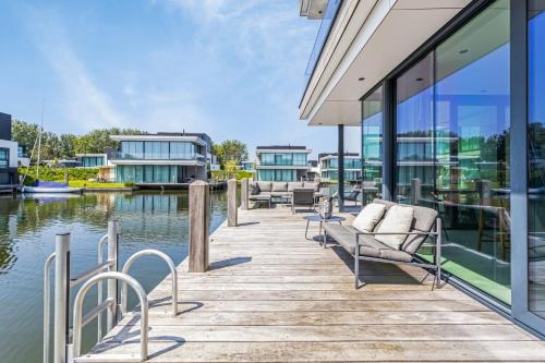 a wooden dock with chairs on it next to the water at Lake House with dock at Lake Veere, Zeeland in Arnemuiden