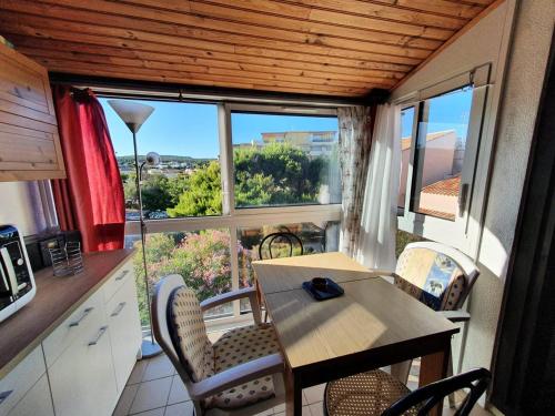 une cuisine avec une table et des chaises et une fenêtre dans l'établissement Appartement pour 4 personnes - 4LBM498, à Narbonne-Plage