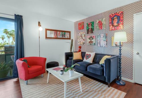 uma sala de estar com um sofá azul e uma cadeira vermelha em Mountain view Cocoon inspired by Frida Kahlo with Pool, Hot Tub, Tennis, Downtown em Palm Springs