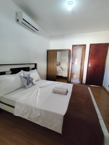a bedroom with a large white bed and a mirror at Residencial 7 Mares in Rio das Ostras