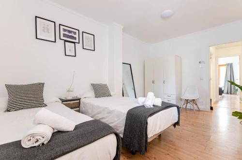 two beds in a bedroom with white walls and wooden floors at Port Apartments in Port d'Alcudia