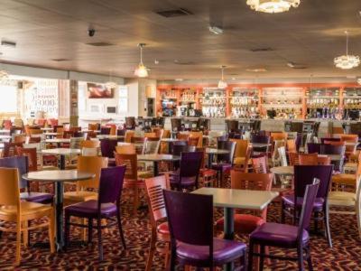 a restaurant with tables and chairs in a room at MOONSTONE Lymington in Leysdown-on-Sea