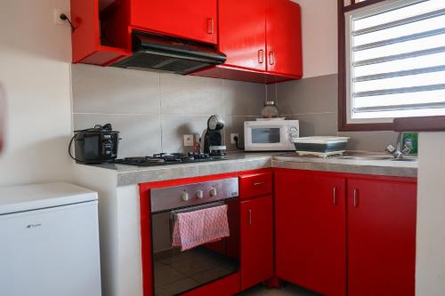 a red kitchen with a stove and a microwave at Au coeur de MANA in Mana