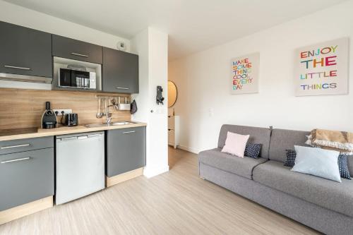 un salon avec un canapé et une cuisine dans l'établissement Studio d'été, à Annecy