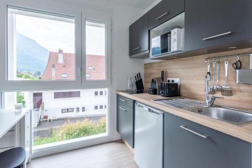 une cuisine avec un évier et une grande fenêtre dans l'établissement Studio d'été, à Annecy