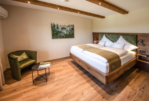 a bedroom with a large bed and a green chair at Chalet Waldzeit in Zachenberg