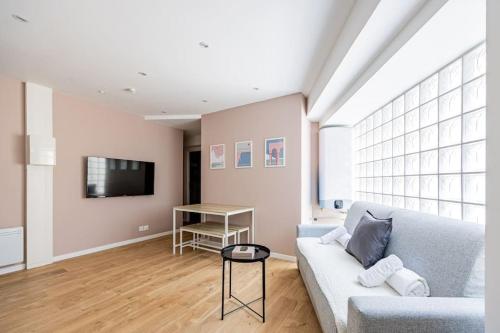 un salon avec un canapé et une télévision dans l'établissement Charme Parisien 6 Personnes, 2 chambres, 19ème, à Paris