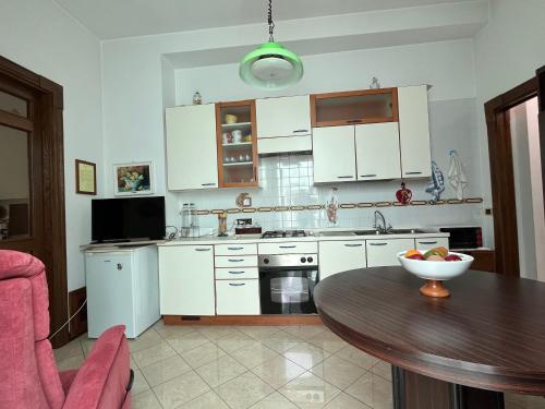 a kitchen with white cabinets and a wooden table at Casa nel Liberty in Canicattini Bagni