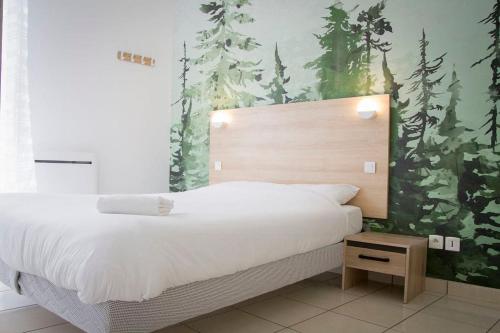 Cette chambre comprend un grand lit blanc et une fresque murale représentant la forêt. dans l'établissement Le Trendy - Parking Wifi Piscine, à Chalezeule
