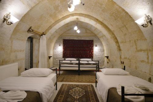 eine Gruppe von drei Betten in einem Zimmer mit einem Torbogen in der Unterkunft View Cave Hotel in Goreme