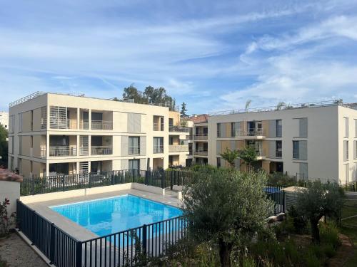 un complexe d'appartements avec une piscine en face de deux bâtiments dans l'établissement Jardin Secret C01, à Antibes