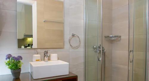 a bathroom with a sink and a shower with a mirror at Bellevue Suites in Agios Nikolaos