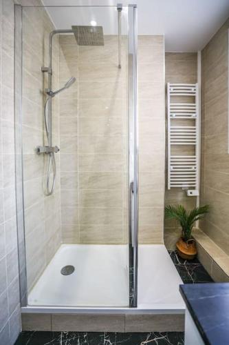 une douche avec une porte vitrée dans une salle de bain dans l'établissement Tranquil retreat in the 16th arrondissement, à Paris