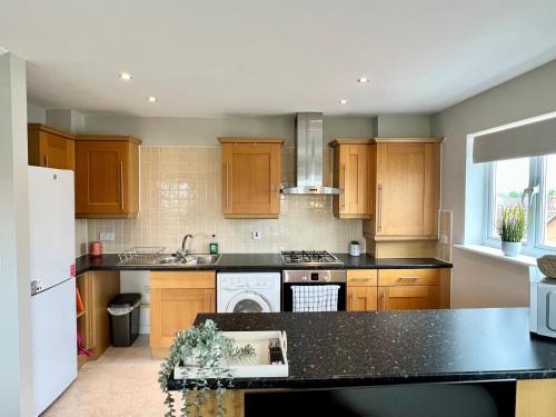 a kitchen with wooden cabinets and a black counter top at This weekend! Two double rooms with parking in quiet well-kept flat in Hatfield