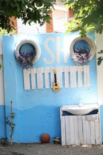 a blue wall with a sink and two windows at Hostel Osho in Tirana