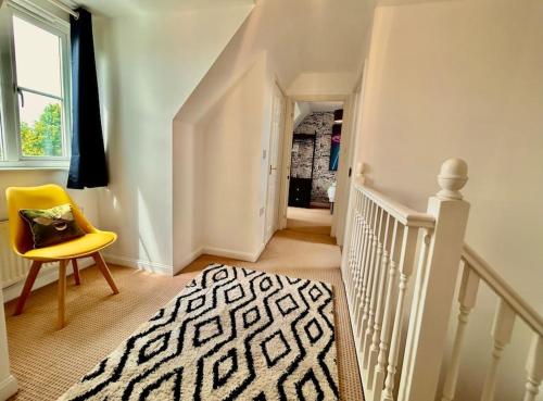 a white staircase with a yellow chair and a rug at 6 Bedroom House - Contractors, Crew, Group, Family in Braintree