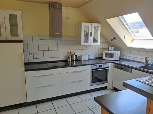 eine Küche mit weißen Geräten und einem Fenster in der Unterkunft Gästehaus Windheim (Büchig) in Stutensee