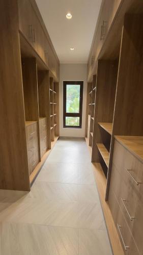a walk in closet with wooden cabinets and a window at Green Palm Self Catering in Anse aux Pins