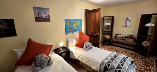 a bedroom with two beds with stuffed animals on them at Elephant Hide of Knysna Guest Lodge in Knysna