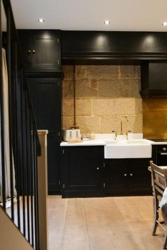 a kitchen with a white sink and black cabinets at The Old Timber Store in Youlgreave