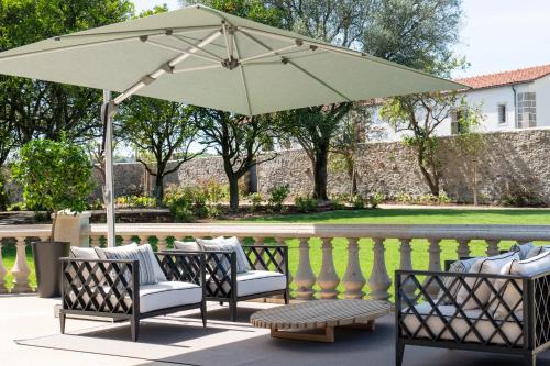 a patio with chairs and an umbrella at Maison Albar - Amoure in Braga
