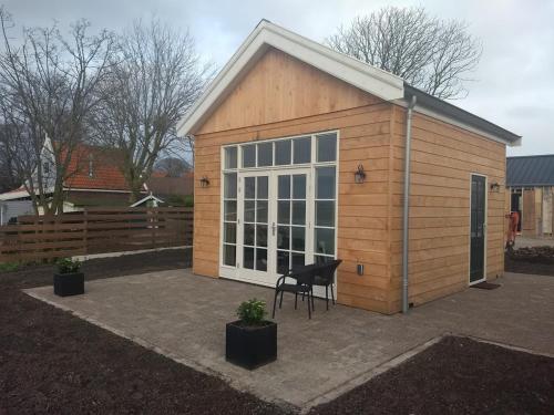 a small wooden building with a chair in front of it at Pronkhuisje in Oterleek