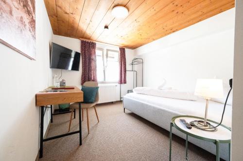 a bedroom with a bed and a desk and a tv at Gasthaus Rössle in Nenzing