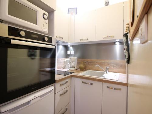 une cuisine avec un micro-ondes et un évier dans l'établissement T2 avec balcon, parking, wifi à 300m centre Mont-Dore - FR-1-608-130, à Le Mont-Dore