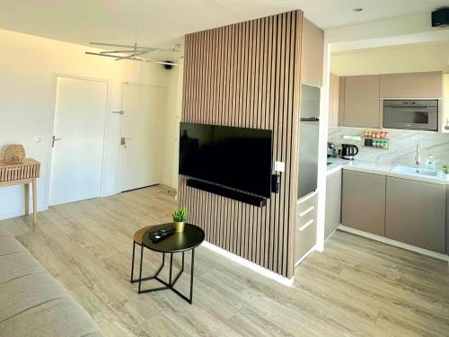 un salon avec une télévision à écran plat sur un mur dans l'établissement Les pieds dans l'eau / F2 avec vue sur Mer, à Houlgate