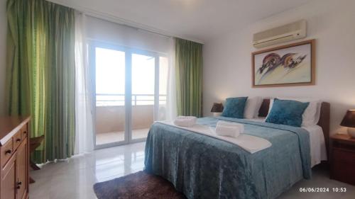 a bedroom with a bed and a large window at Casa Jardins da Rocha in Portimão