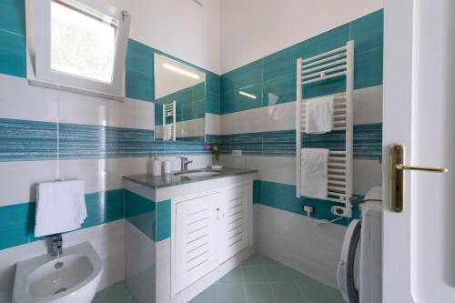 a bathroom with green and white tile and a sink at Casa Michele, 200 steps to heaven in Praiano
