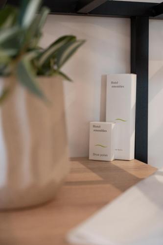 two white boxes and a potted plant on a shelf at IRA - ΗΡΑ Hotel in Kalamata