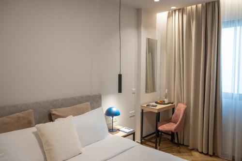 a bedroom with a bed and a desk and a chair at IRA - ΗΡΑ Hotel in Kalamata