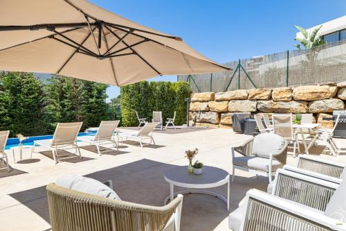Un patio con sillas y mesas y una sombrilla. en ViVi Homes -Villa Yara Pool, Sauna, Spa & Garden, en Mijas
