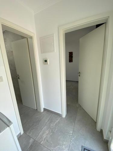 a hallway with two white doors and a tile floor at Kevin&Jessica Rooms in Giarmata