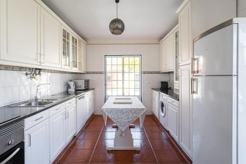 a kitchen with white cabinets and a table in it at GuestReady - Peaceful Escape in Praia de Mira in Praia de Mira
