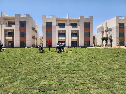 a group of people standing in a field in front of a building at Mohamed Afifi GAIA Ras El-Hekma - Penthouse 2BR- Families Only in Ras Elhekma